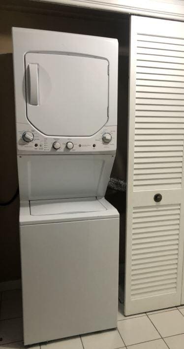 laundry room featuring light tile patterned flooring and stacked washer and dryer