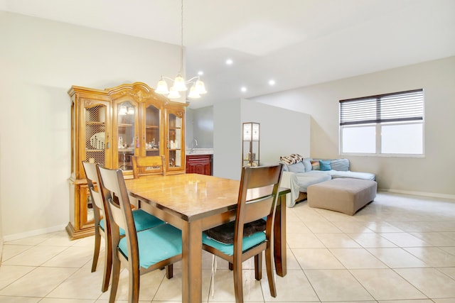 tiled dining space featuring sink, vaulted ceiling, and an inviting chandelier