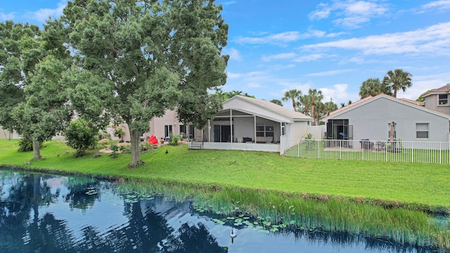 back of house featuring a yard, a sunroom, and a water view