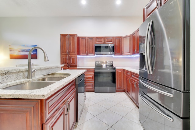 kitchen featuring light stone countertops, appliances with stainless steel finishes, sink, and light tile patterned floors