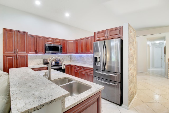 kitchen with light stone counters, an island with sink, stainless steel appliances, and sink