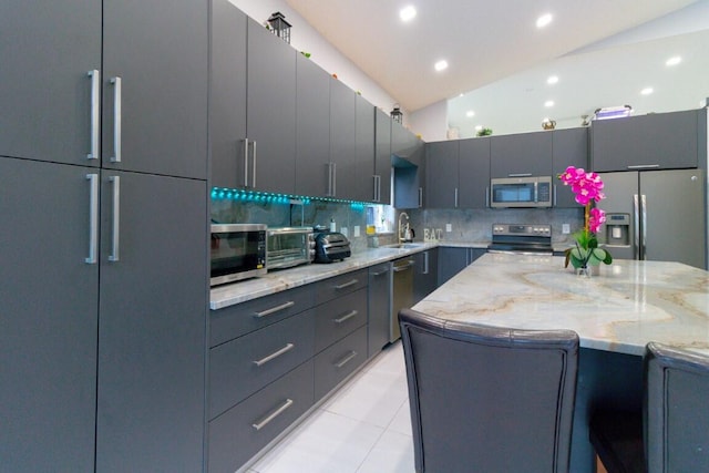 kitchen featuring tasteful backsplash, sink, vaulted ceiling, stainless steel appliances, and light stone countertops