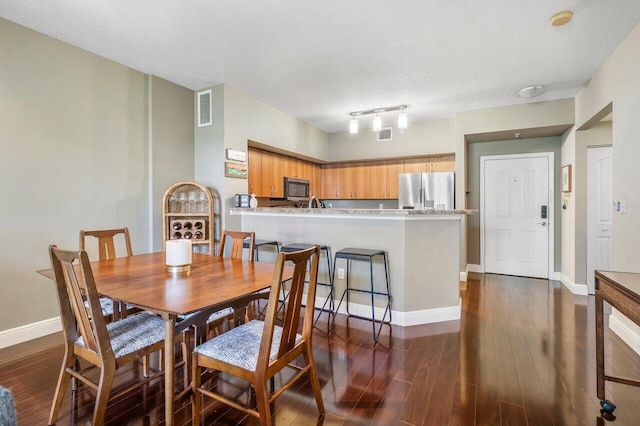 dining area featuring a textured ceiling and dark wood-type flooring