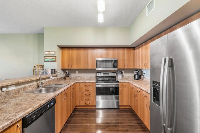 kitchen featuring light stone counters, a textured ceiling, dark hardwood / wood-style floors, sink, and appliances with stainless steel finishes