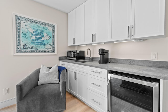 kitchen with wine cooler, white cabinetry, light hardwood / wood-style flooring, and sink