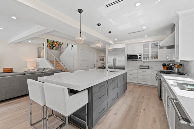 kitchen featuring decorative backsplash, high end appliances, light hardwood / wood-style flooring, white cabinetry, and a large island