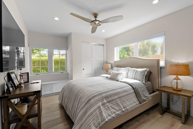 bedroom with ceiling fan, light hardwood / wood-style flooring, and multiple windows