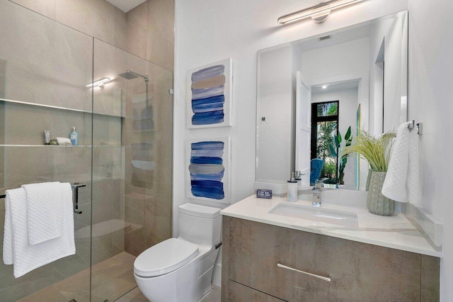 bathroom featuring tile patterned flooring, a shower with shower door, vanity, and toilet