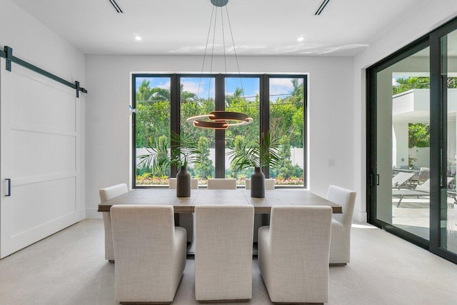 dining area with a barn door, a chandelier, and light colored carpet