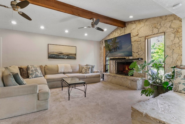 carpeted living room with a textured ceiling, a stone fireplace, lofted ceiling with beams, and ceiling fan