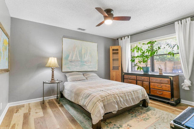 bedroom with light wood-type flooring, a textured ceiling, and ceiling fan