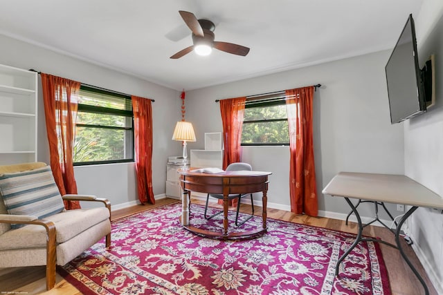 home office with light wood-type flooring and ceiling fan