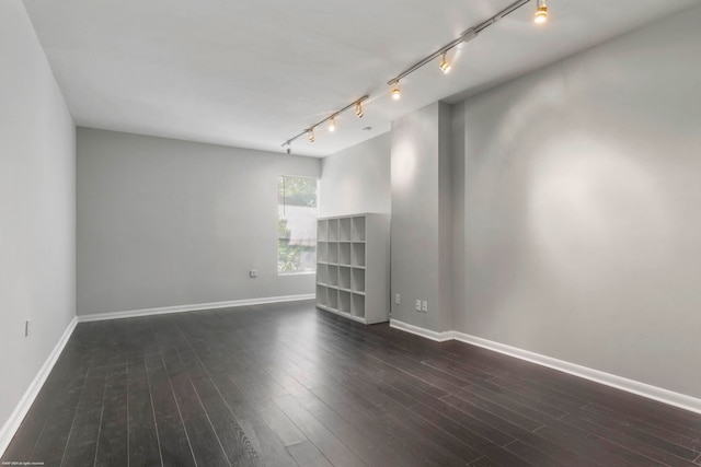 spare room featuring track lighting and dark hardwood / wood-style flooring