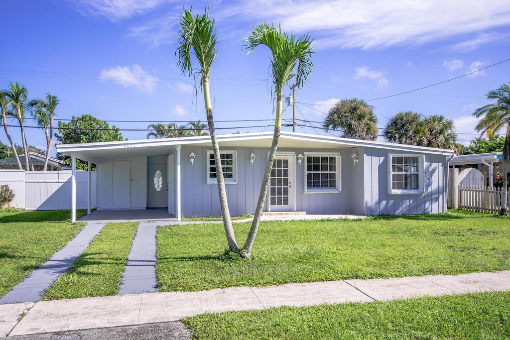 11637 Balsam Dr, Royal Palm Beach, FL 33411 - view of front of house featuring board and batten siding, a front lawn, fence, and driveway