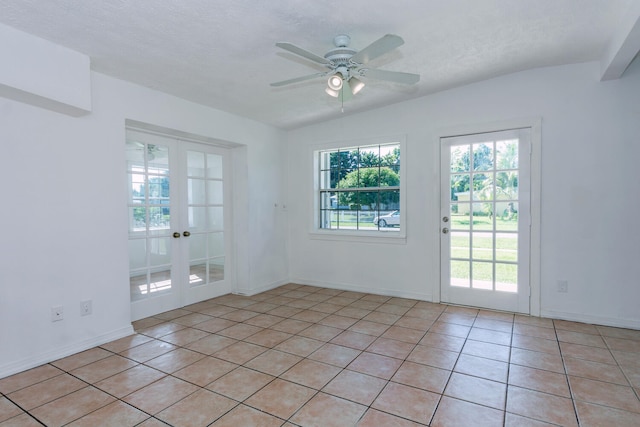 empty room featuring ceiling fan, light tile patterned floors, french doors, a textured ceiling, and vaulted ceiling