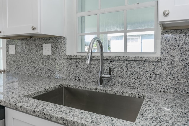 kitchen with decorative backsplash, white cabinetry, plenty of natural light, and sink