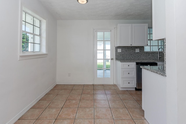 kitchen with decorative backsplash, white cabinets, dark stone countertops, and a healthy amount of sunlight