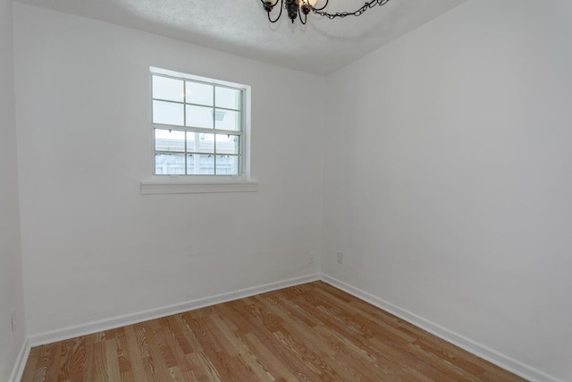 empty room with light hardwood / wood-style floors and a chandelier