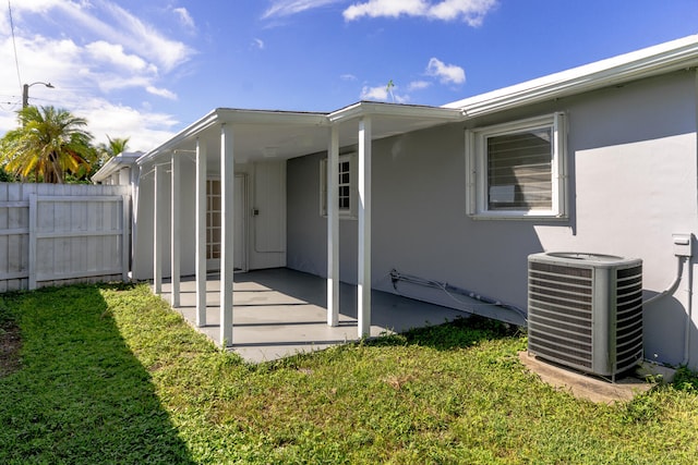 entrance to property featuring a yard, a patio, and central AC