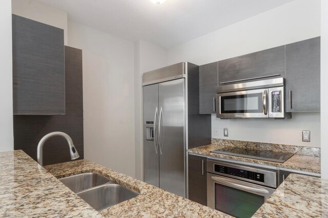 kitchen featuring light stone countertops, sink, and stainless steel appliances