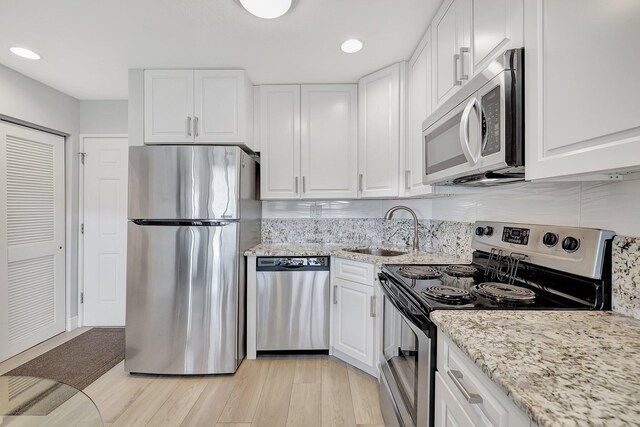 kitchen featuring stainless steel appliances, white cabinetry, sink, and light wood-type flooring