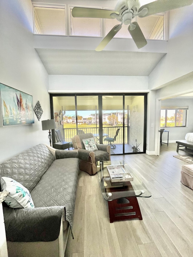 living room featuring a high ceiling, wood-type flooring, and ceiling fan