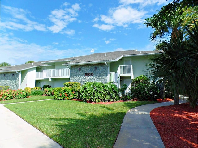 view of front of property featuring a balcony and a front yard