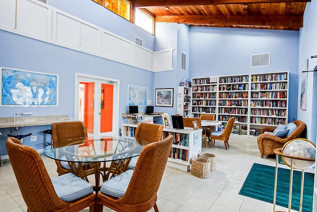 dining space with a high ceiling, light tile patterned floors, wooden ceiling, and beamed ceiling