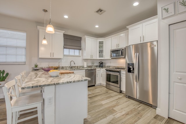 kitchen featuring a peninsula, white cabinetry, light wood-style floors, visible vents, and appliances with stainless steel finishes