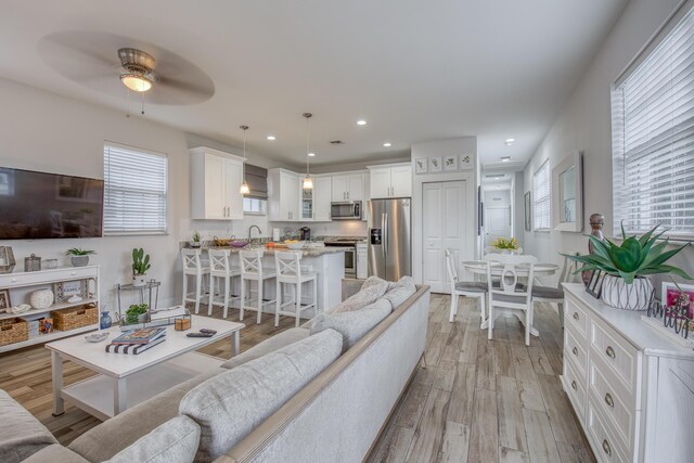 living room featuring light hardwood / wood-style floors, plenty of natural light, and ceiling fan