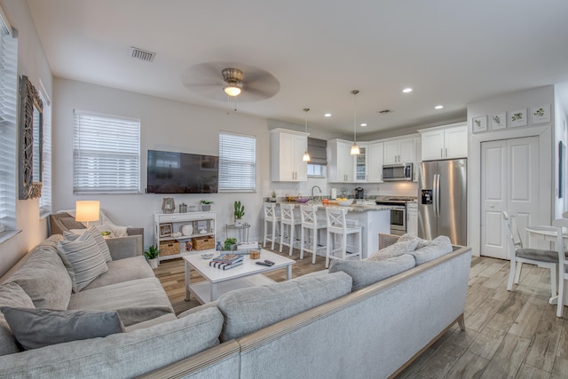 living room with light hardwood / wood-style flooring, ceiling fan, and sink