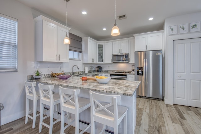 kitchen featuring pendant lighting, stainless steel appliances, and white cabinets