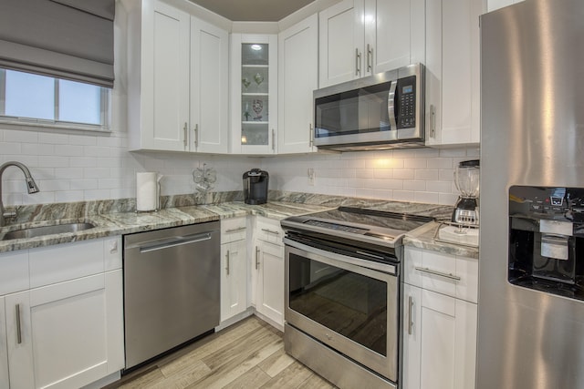 kitchen featuring white cabinets, stainless steel appliances, light hardwood / wood-style floors, and light stone countertops