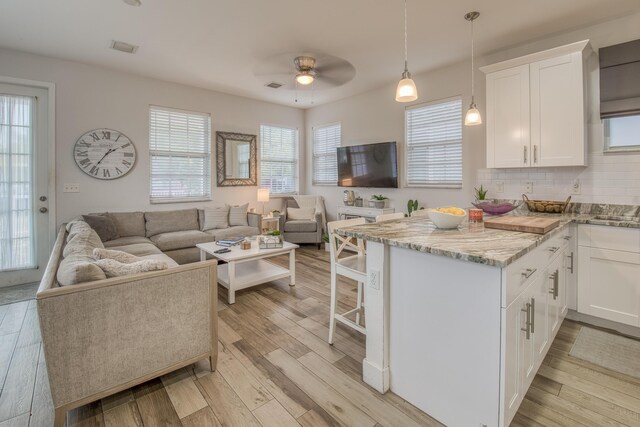 kitchen with hanging light fixtures, white cabinetry, ceiling fan, and light hardwood / wood-style flooring