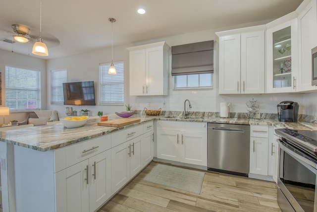 kitchen with a peninsula, light wood-style flooring, white cabinetry, appliances with stainless steel finishes, and a sink