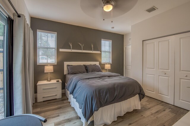 bedroom with light wood-type flooring, ceiling fan, and a closet