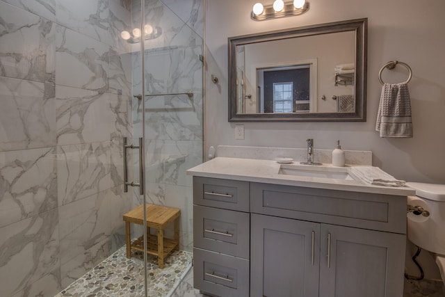 bathroom with tiled shower, vanity, and toilet