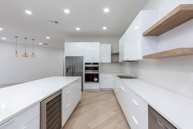 kitchen with white cabinets, hanging light fixtures, wine cooler, light wood-type flooring, and appliances with stainless steel finishes