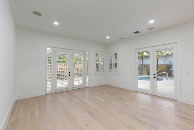 spare room with french doors, light wood-type flooring, and a wealth of natural light