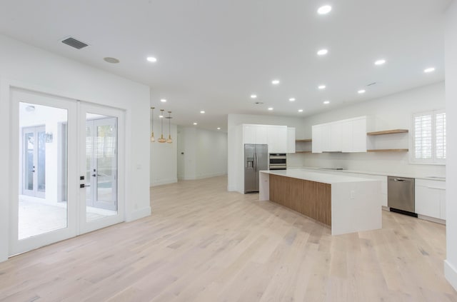 kitchen featuring white cabinets, a kitchen island, light wood-type flooring, and stainless steel appliances