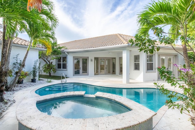 rear view of property with french doors, a patio area, and a pool with hot tub