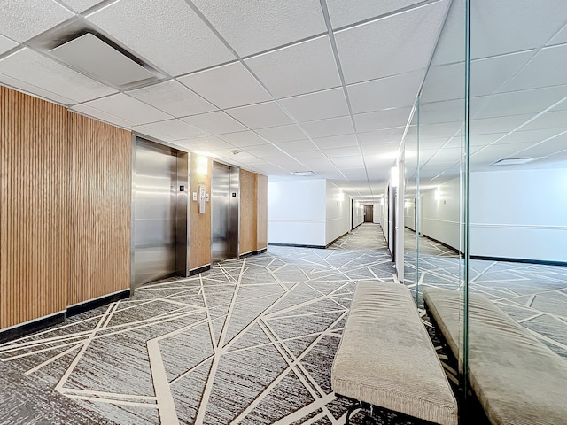 basement with carpet, a drop ceiling, and elevator