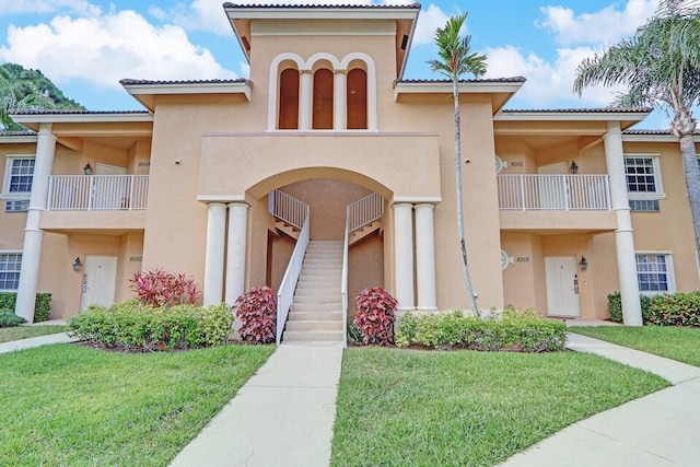 view of front of property with a balcony and a front lawn