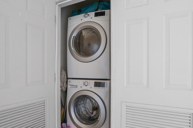 clothes washing area featuring stacked washer and clothes dryer