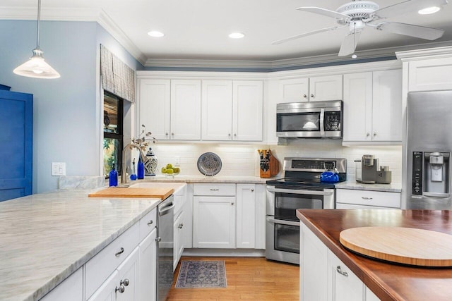 kitchen with ornamental molding, white cabinets, ceiling fan, and appliances with stainless steel finishes