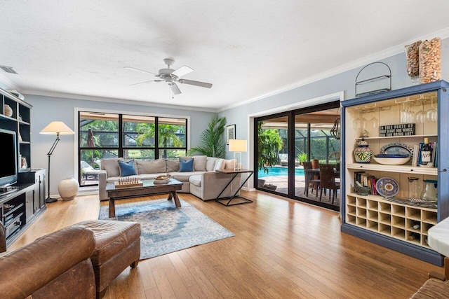 living room with ceiling fan, a textured ceiling, ornamental molding, and wood-type flooring