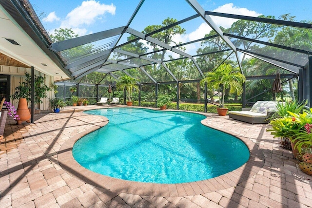 view of pool featuring glass enclosure and a patio