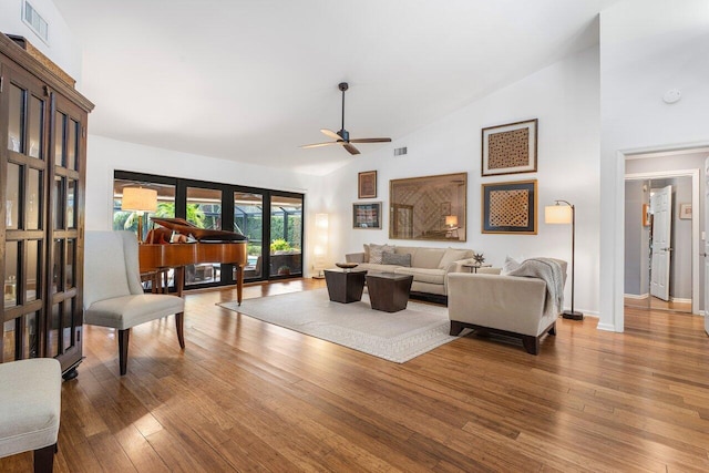 living room with hardwood / wood-style floors, ceiling fan, and high vaulted ceiling