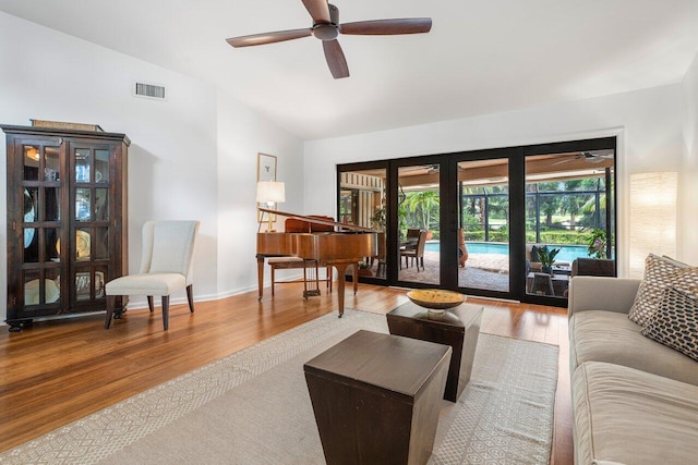 living room featuring wood-type flooring, vaulted ceiling, ceiling fan, and french doors