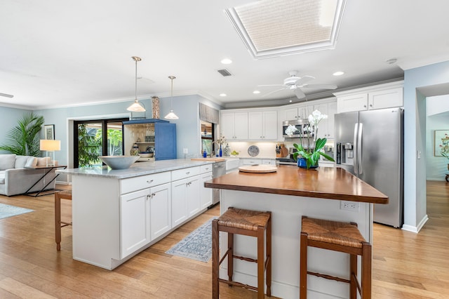 kitchen with white cabinets, appliances with stainless steel finishes, and a kitchen bar